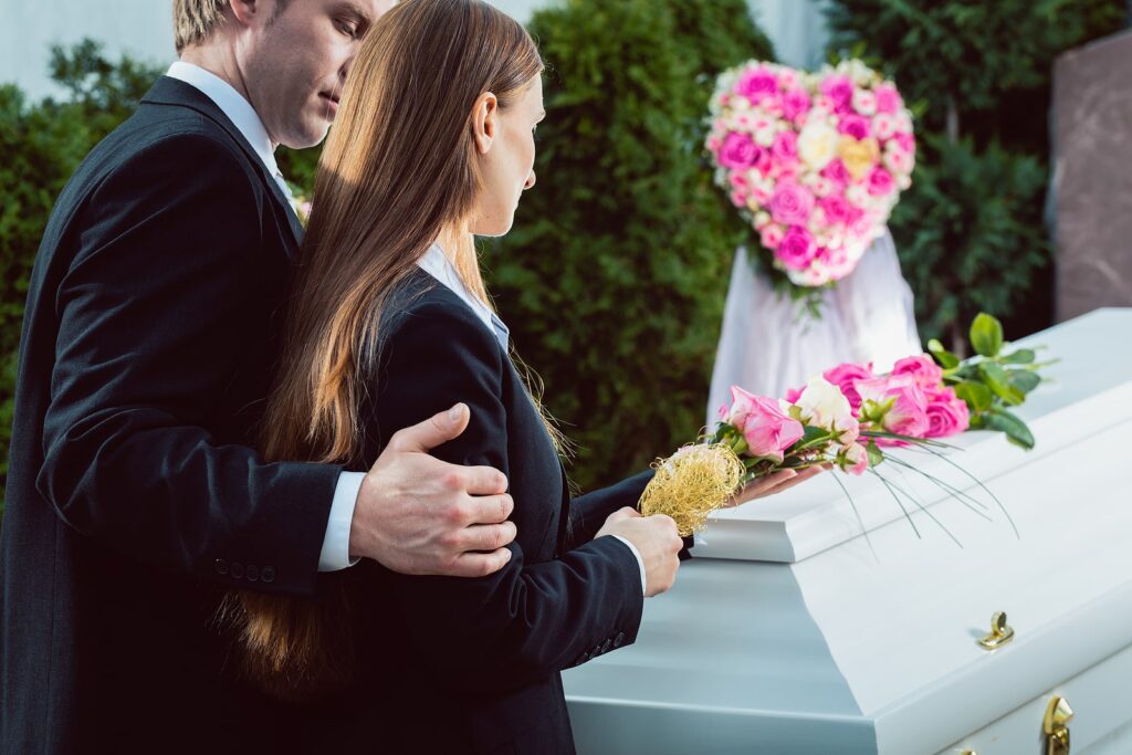 Two people standing over a coffin image on Tegeler's website
