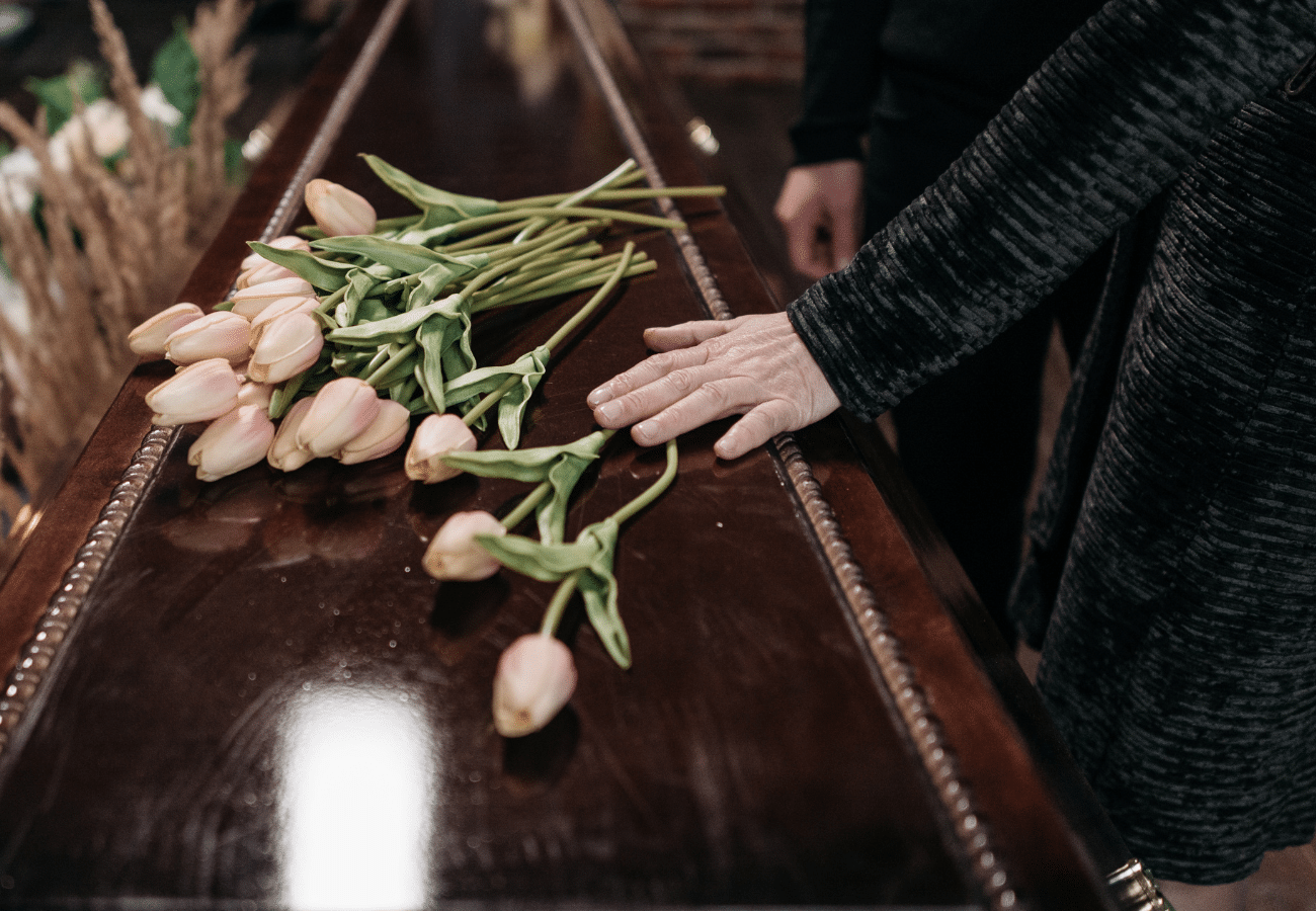 Image of a person's hand on a casket along with tulips on Tegeler's website