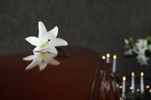 picture from inside a funeral home depicting a coffin with a white flower on it.