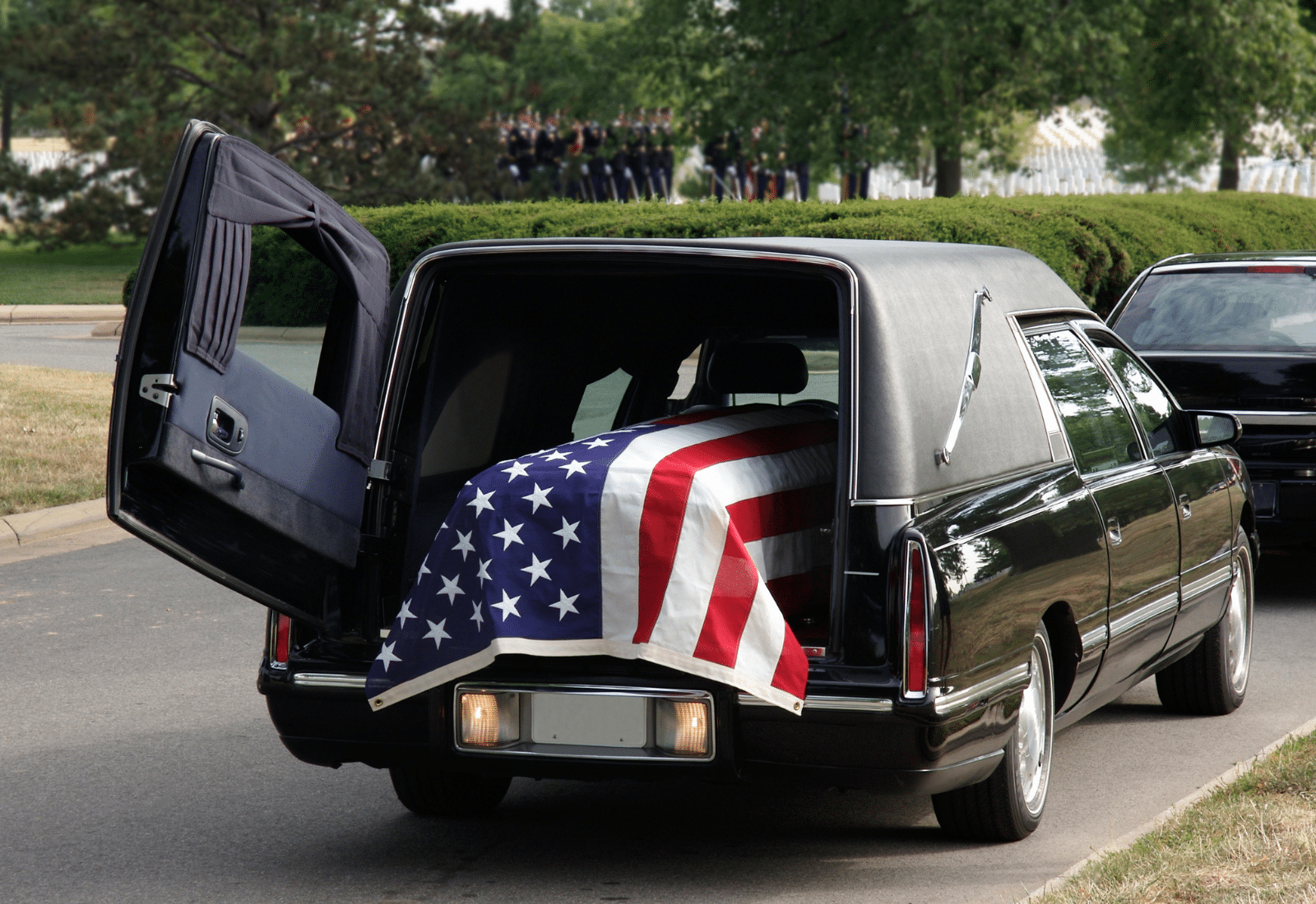 Image of a hearse carrying a casket decorated with the American flag