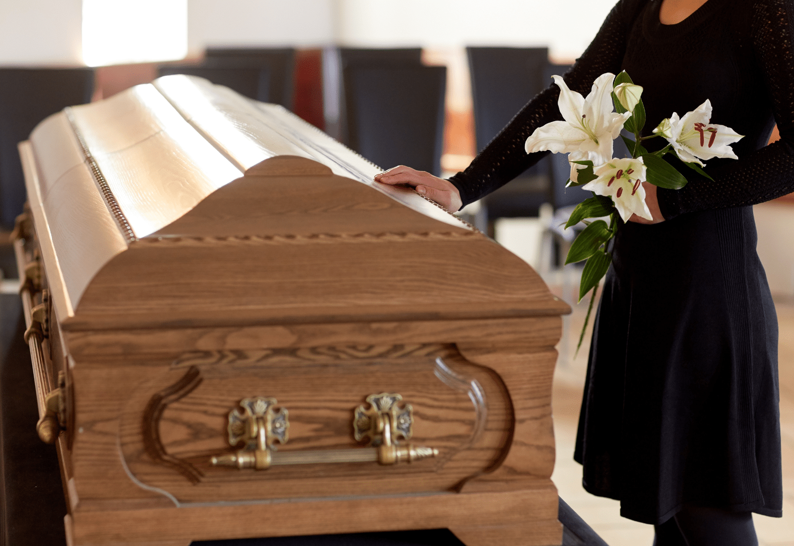 Image of a woman holding flowers beside a casket